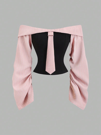 Two-tone off-shoulder black top with striped pink sleeves and an attached necktie detail laid flat against a neutral background