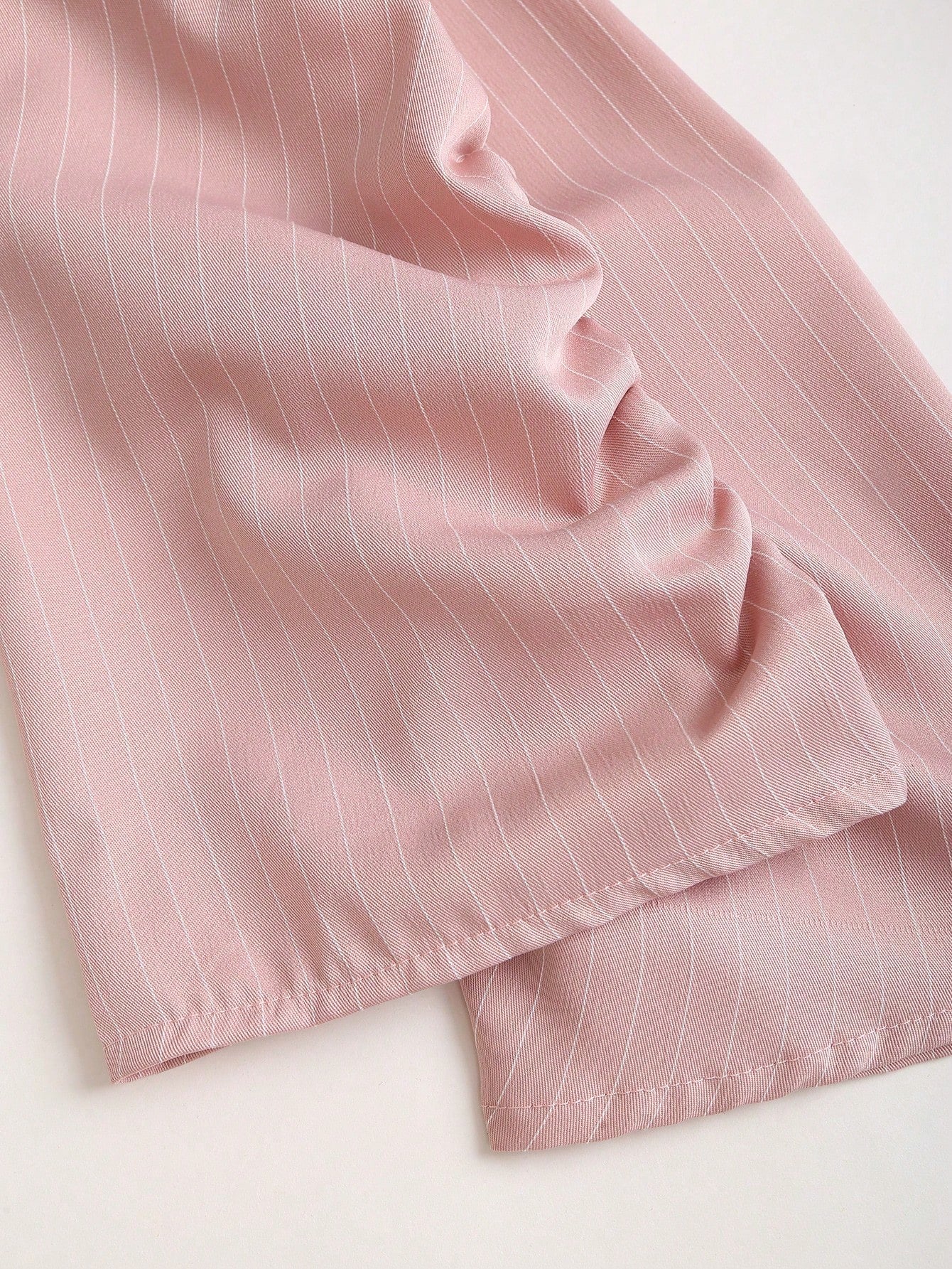 Two-tone off-shoulder black top with striped pink sleeves and an attached necktie detail laid flat against a neutral background