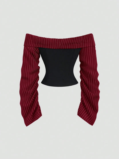 Two-tone off-shoulder black top with striped red sleeves and an attached necktie detail laid flat against a neutral background