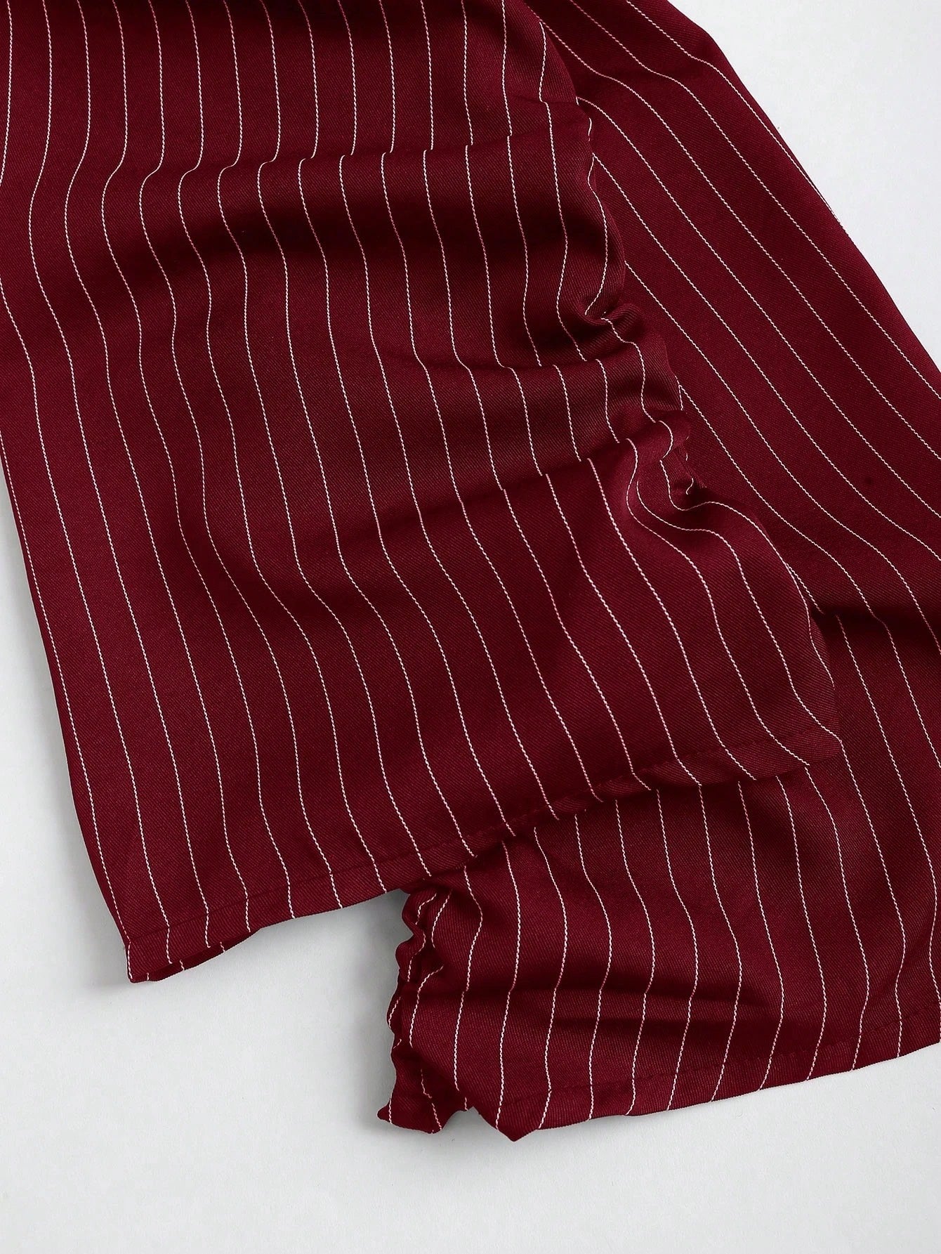 Two-tone off-shoulder black top with striped red sleeves and an attached necktie detail laid flat against a neutral background