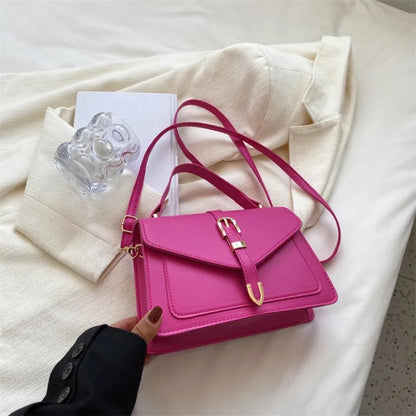 Pink handbag on a white surface with a hand holding it
