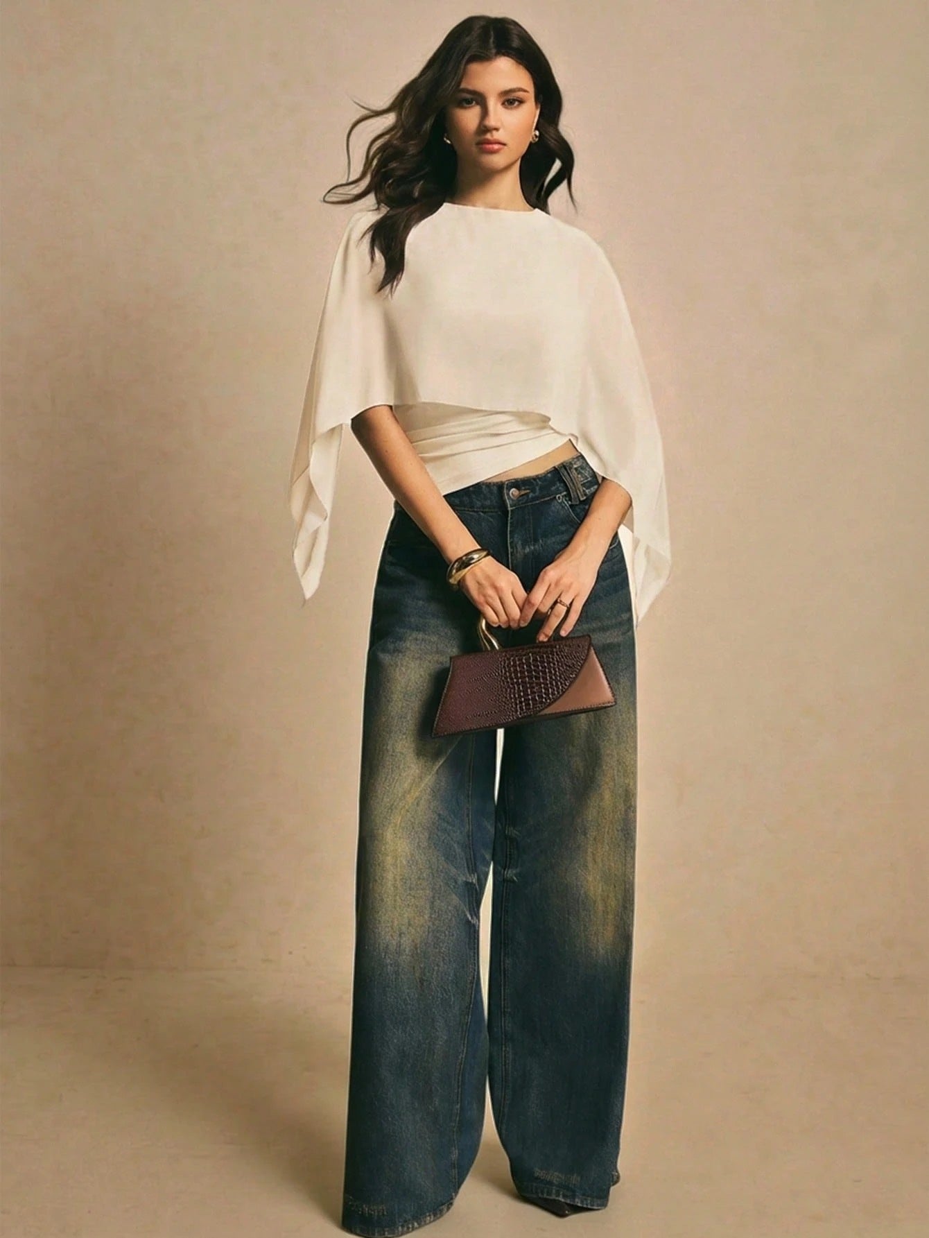 Woman wearing a apricot solid color elegant shawl blouse with cape sleeves paired with dark denim jeans