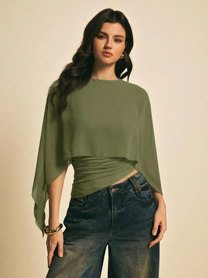 Woman wearing a Army Green solid color elegant shawl blouse with cape sleeves paired with dark denim jeans