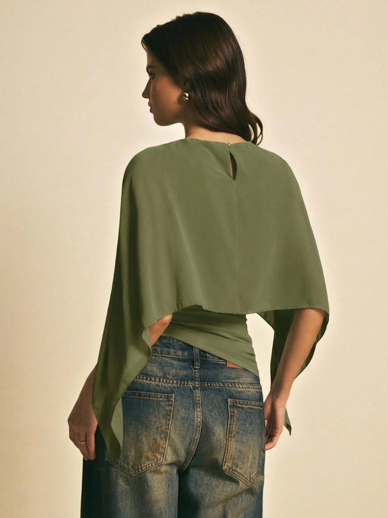 Woman wearing a Army Green solid color elegant shawl blouse with cape sleeves paired with dark denim jeans