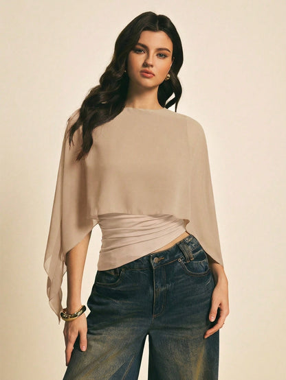 Woman wearing a Khaki solid color elegant shawl blouse with cape sleeves paired with dark denim jeans