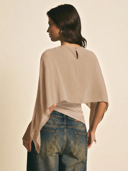 Woman wearing a Khaki solid color elegant shawl blouse with cape sleeves paired with dark denim jeans