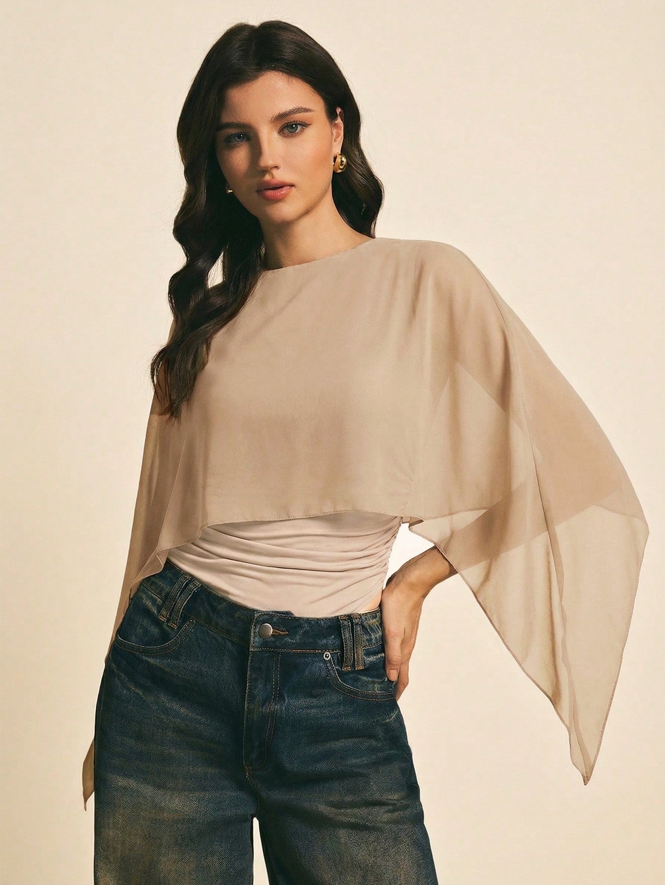 Woman wearing a Khaki solid color elegant shawl blouse with cape sleeves paired with dark denim jeans