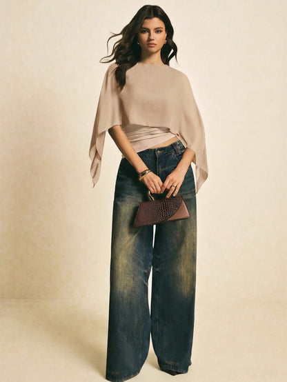 Woman wearing a Khaki solid color elegant shawl blouse with cape sleeves paired with dark denim jeans