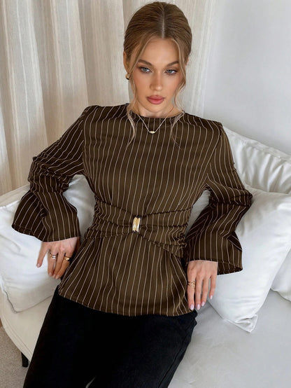 Woman wearing a brown pinstripe long sleeve blouse featuring a metal ring decor waist detail and dark trousers