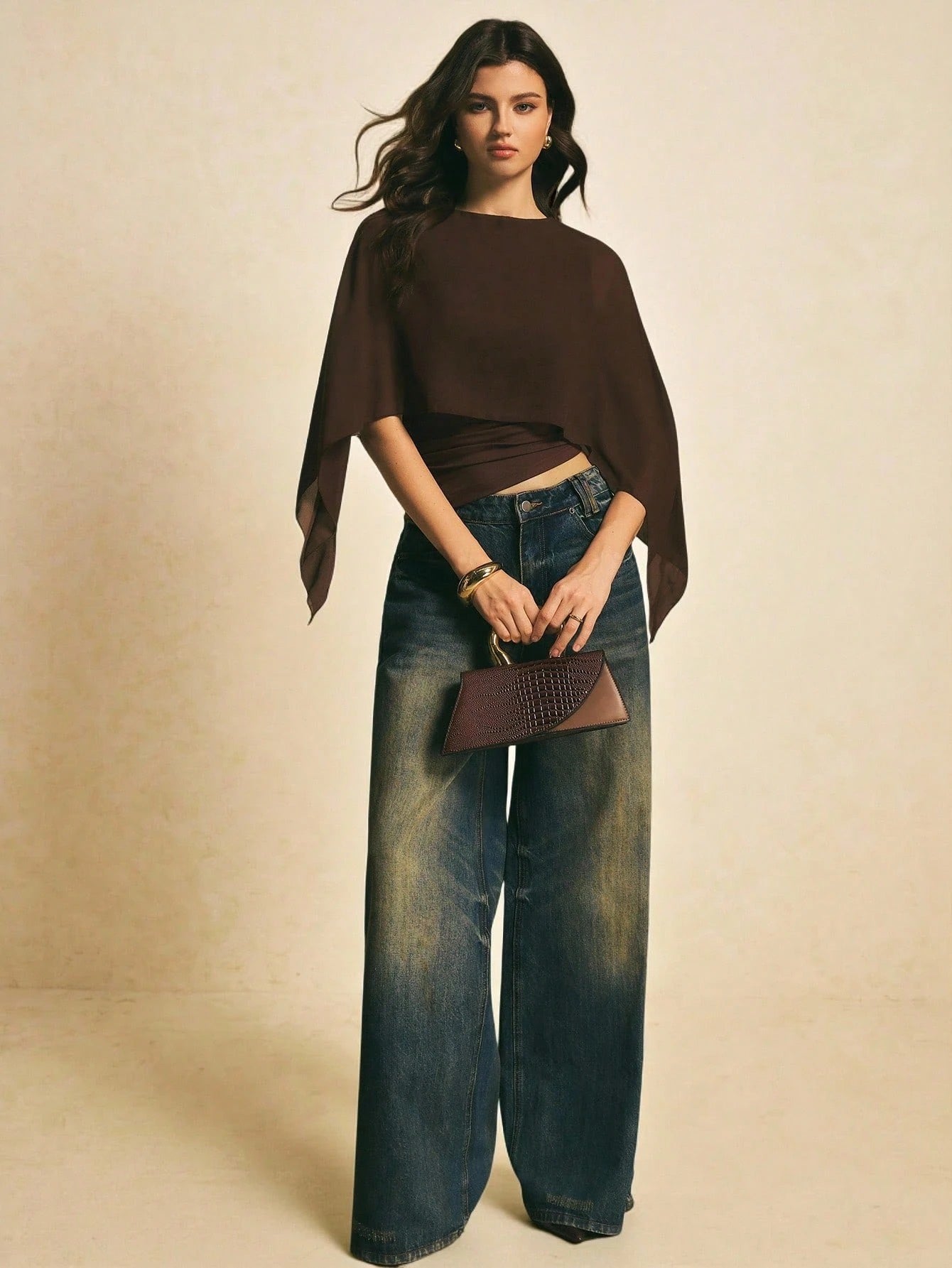 Woman wearing a brown solid color elegant shawl blouse with cape sleeves paired with dark denim jeans