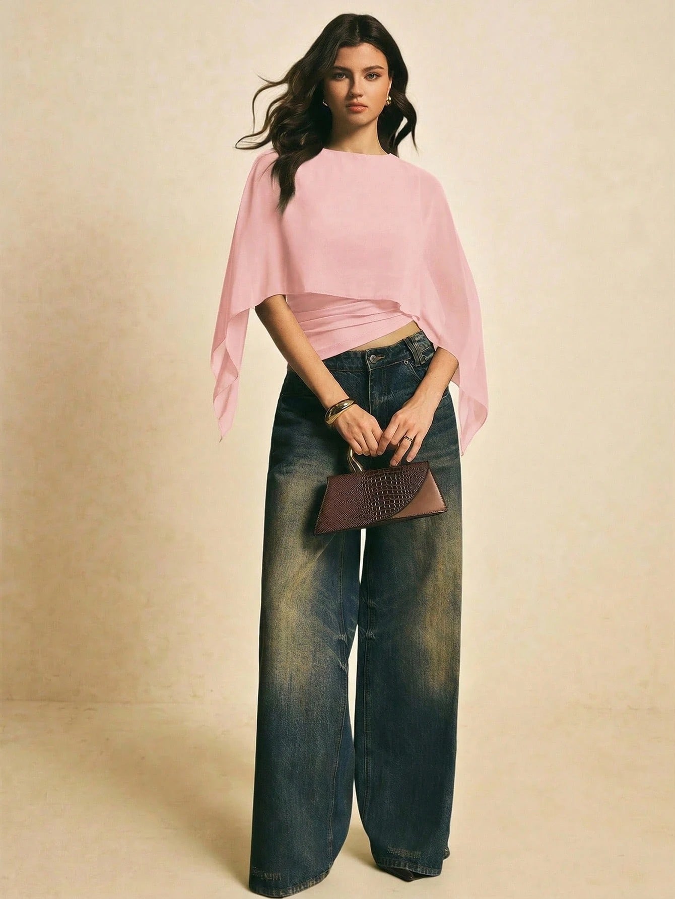 Woman wearing a pink solid color elegant shawl blouse with cape sleeves paired with dark denim jeans
