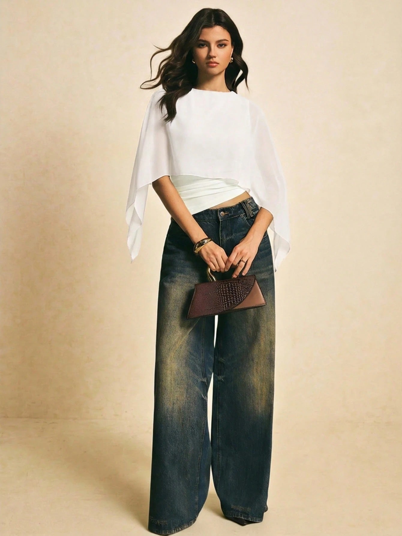 Woman wearing a white solid color elegant shawl blouse with cape sleeves paired with dark denim jeans