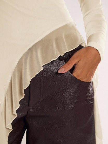 Woman wearing an apricot fitted long sleeve top with an asymmetric ruffle hem paired with dark brown faux leather pants