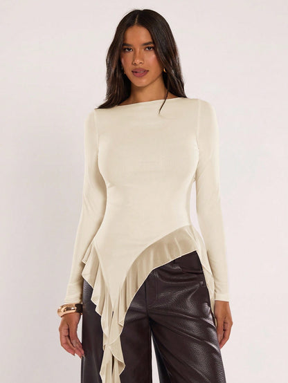 Woman wearing an apricot fitted long sleeve top with an asymmetric ruffle hem paired with dark brown faux leather pants