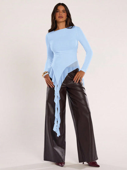 Woman wearing an baby blue fitted long sleeve top with an asymmetric ruffle hem paired with dark brown faux leather pants