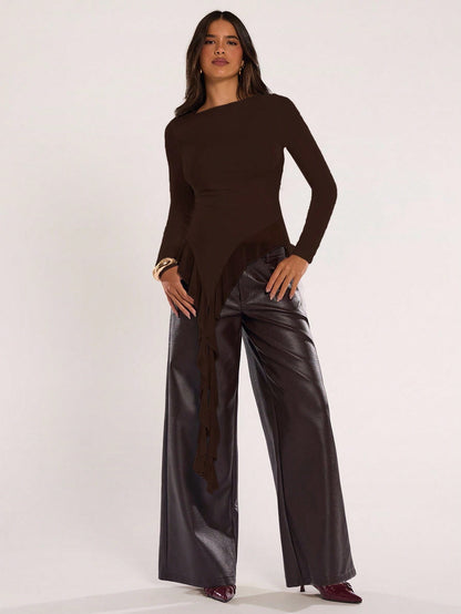 Woman wearing an coffee brown fitted long sleeve top with an asymmetric ruffle hem paired with dark brown faux leather pants