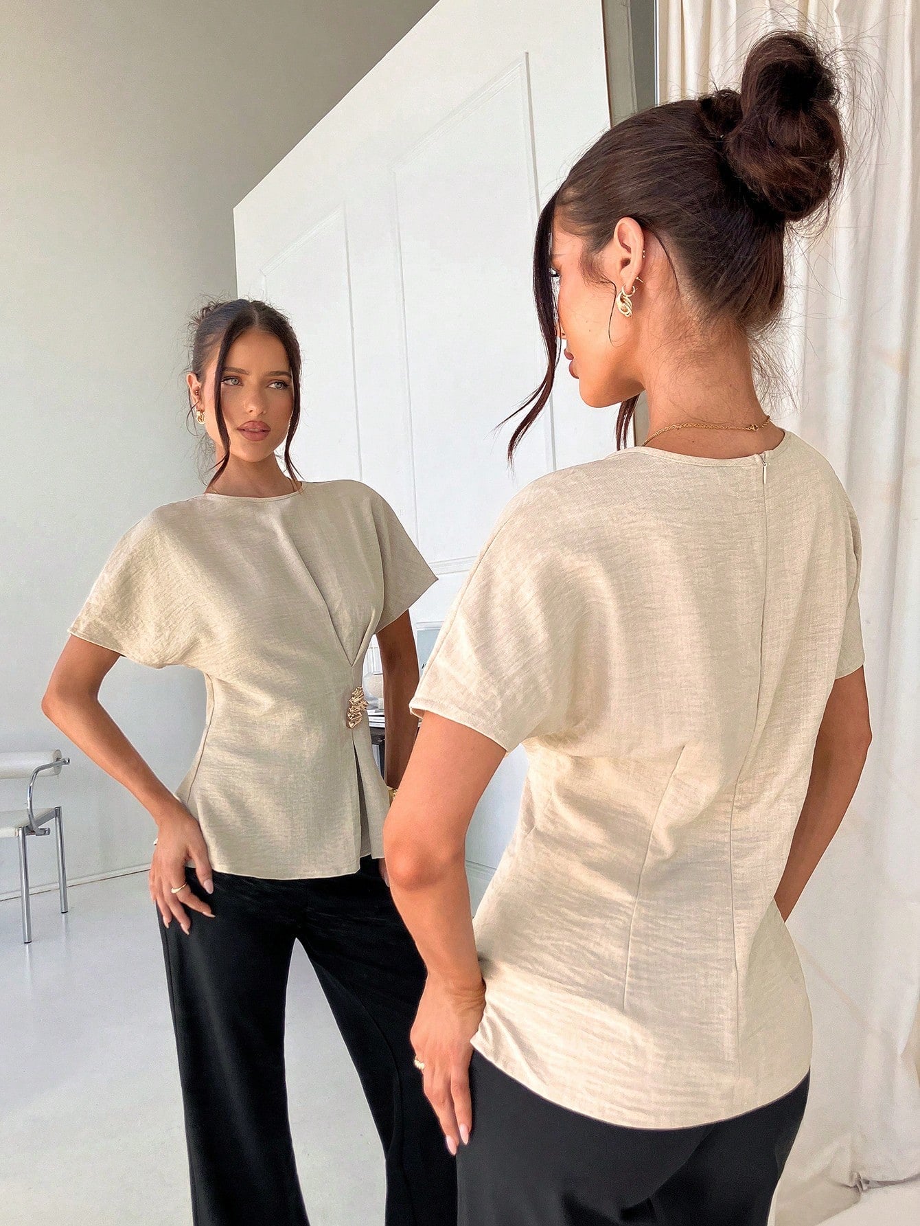 Women's apricot short-sleeve round neck blouse with a statement gold side waist buckle paired with black trousers for an office look.