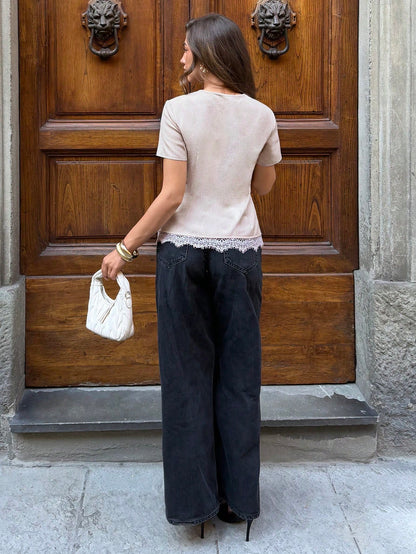 Women's apricot short sleeve slim-fit shirt with gold metal buttons and a white lace trim hem paired with black jeans.