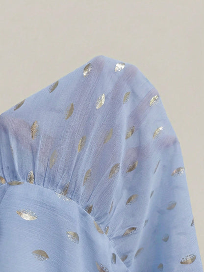 Women's baby blue long-sleeve chiffon blouse with metallic foil dots, a V-neck, a scarf tie, and a tiered ruffled hem paired with blue jeans.