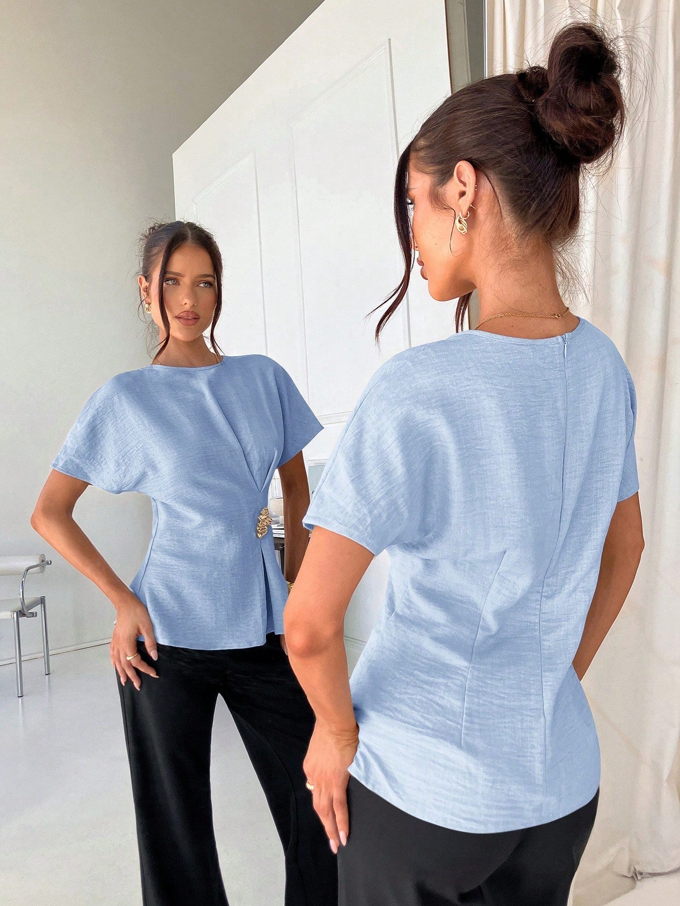 Women's baby blue short-sleeve round neck blouse with a statement gold side waist buckle paired with black trousers for an office look.