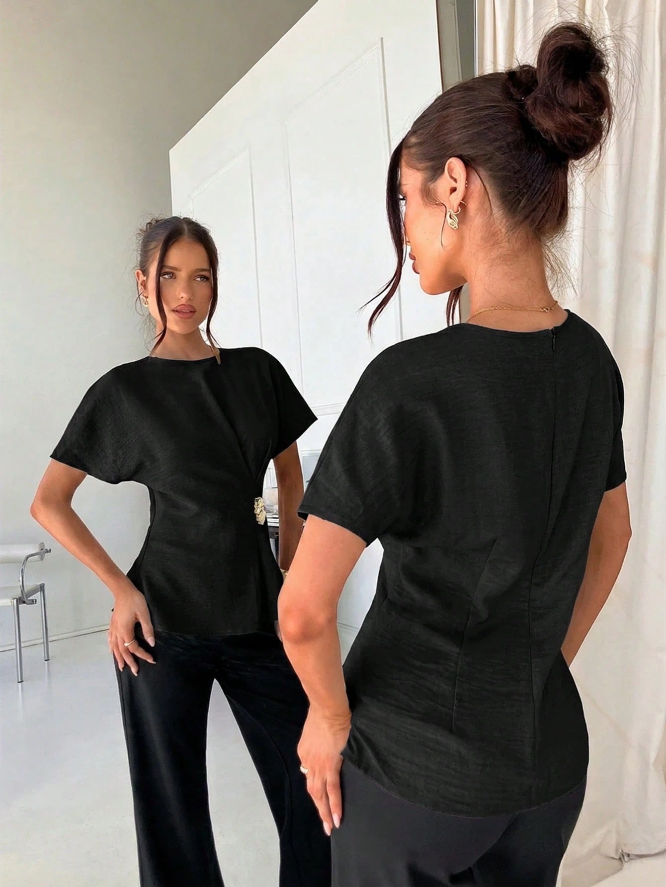 Women's black short-sleeve round neck blouse with a statement gold side waist buckle paired with black trousers for an office look.
