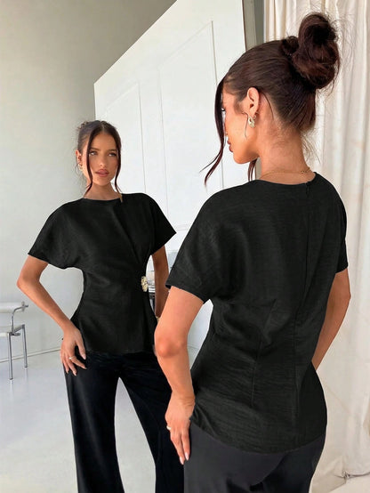 Women's black short-sleeve round neck blouse with a statement gold side waist buckle paired with black trousers for an office look.