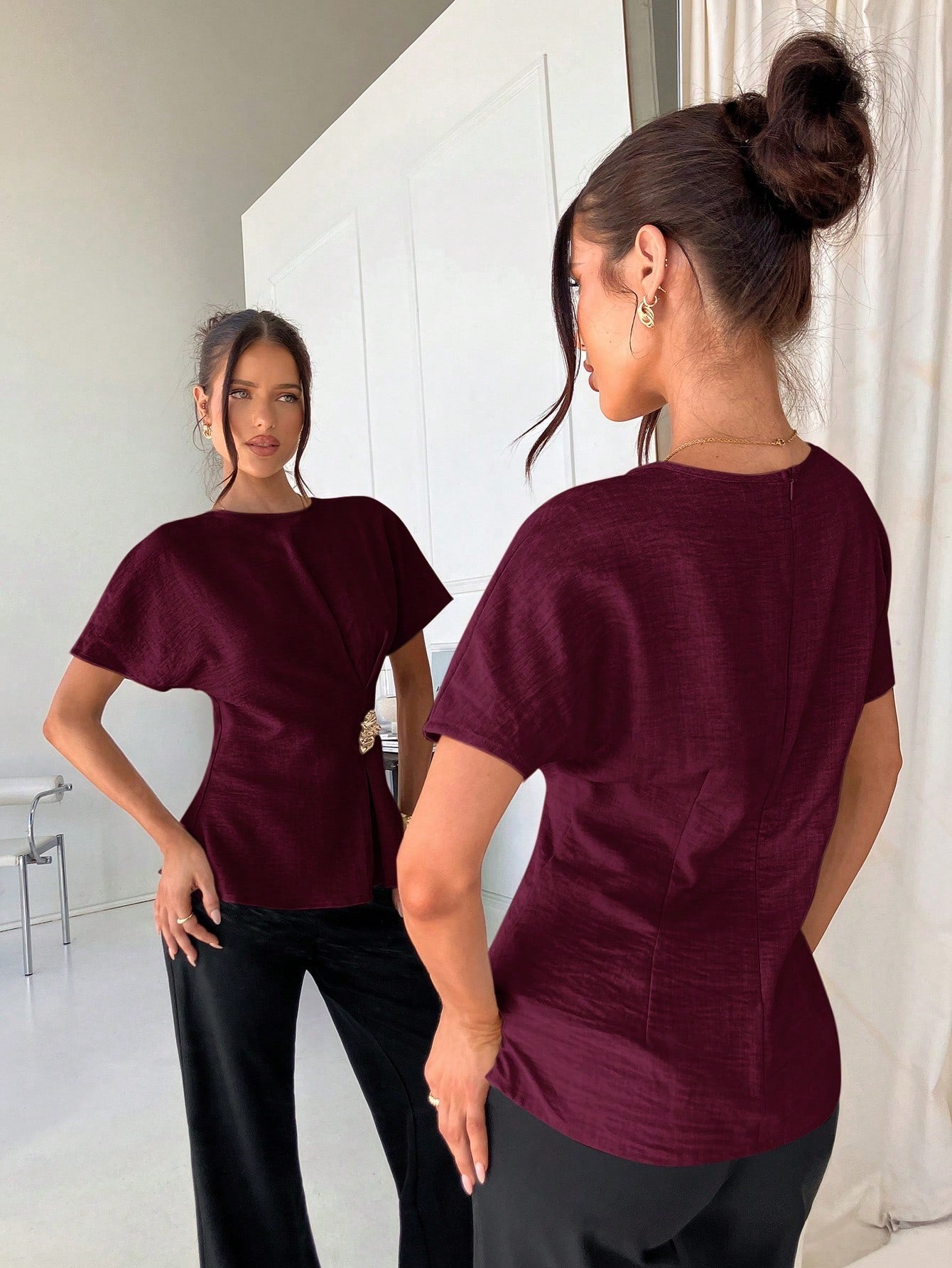 Women's burgundy short-sleeve round neck blouse with a statement gold side waist buckle paired with black trousers for an office look.