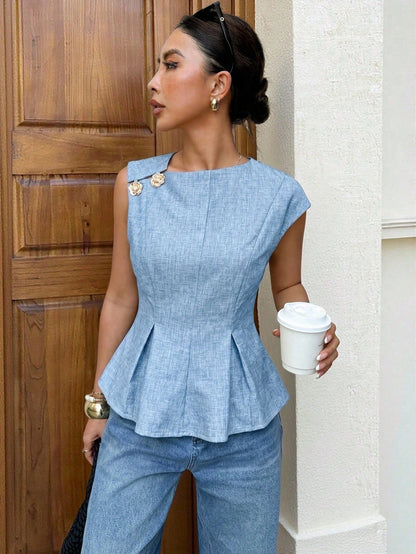 Women's minimalist baby blue sleeveless peplum blouse with gold button accents and a pleated flare hem paired with blue jeans.