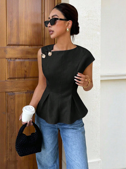 Women's minimalist black sleeveless peplum blouse with gold button accents and a pleated flare hem paired with blue jeans.