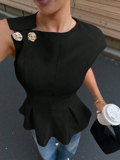 Women's minimalist black sleeveless peplum blouse with gold button accents and a pleated flare hem paired with blue jeans.