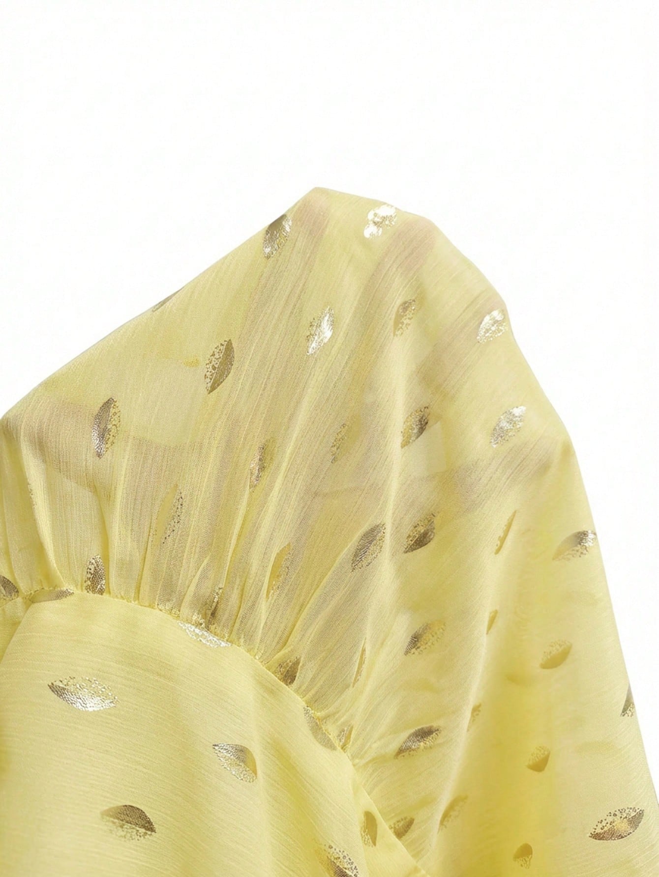 Women's yellow long-sleeve chiffon blouse with metallic foil dots, a V-neck, a scarf tie, and a tiered ruffled hem paired with blue jeans.