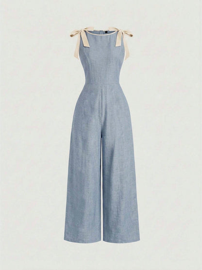 blue wide-leg sleeveless jumpsuit featuring contrast brown shoulder bow ties and trim laid flat against a neutral background
