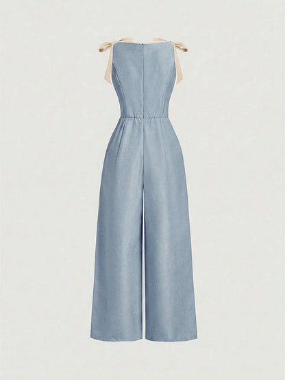 blue wide-leg sleeveless jumpsuit featuring contrast brown shoulder bow ties and trim laid flat against a neutral background