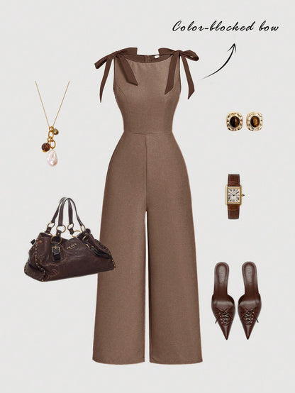 brown wide-leg sleeveless jumpsuit featuring contrast brown shoulder bow ties and trim laid flat against a neutral background