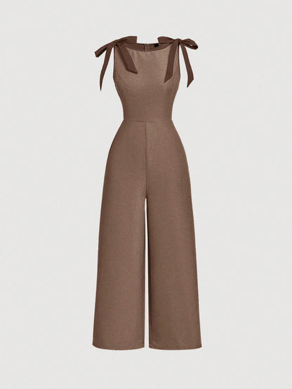 brown wide-leg sleeveless jumpsuit featuring contrast brown shoulder bow ties and trim laid flat against a neutral background