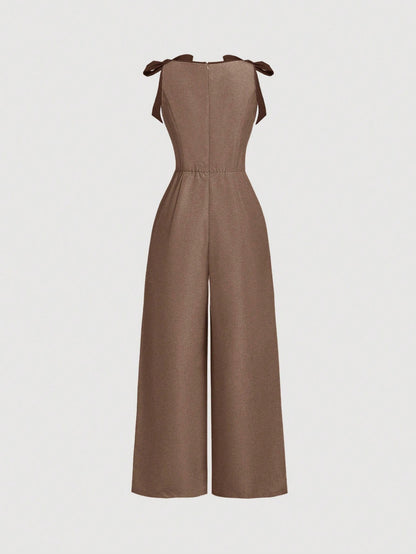 brown wide-leg sleeveless jumpsuit featuring contrast brown shoulder bow ties and trim laid flat against a neutral background